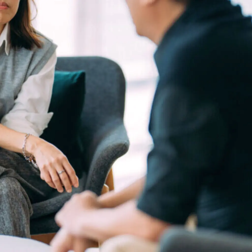Two people sitting in chairs having a focused conversation in an office.